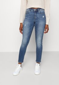 Jeans blu a vita media con vestibilità slim, dotati di leggeri dettagli di usura, classico design a cinque tasche e leggero restringimento alla caviglia.