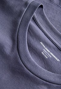 Lilla bomulds-T-shirt med ribbet rund hals, glat tekstur og mærke med plejeoplysninger på indersiden af kraven.