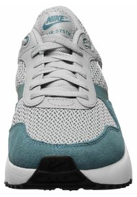 Le sneakers Nike Air presentano una tomaia in rete grigia con accenti in suede teal, lacci piatti testurizzati e una linguetta imbottita con branding. Suola nera.