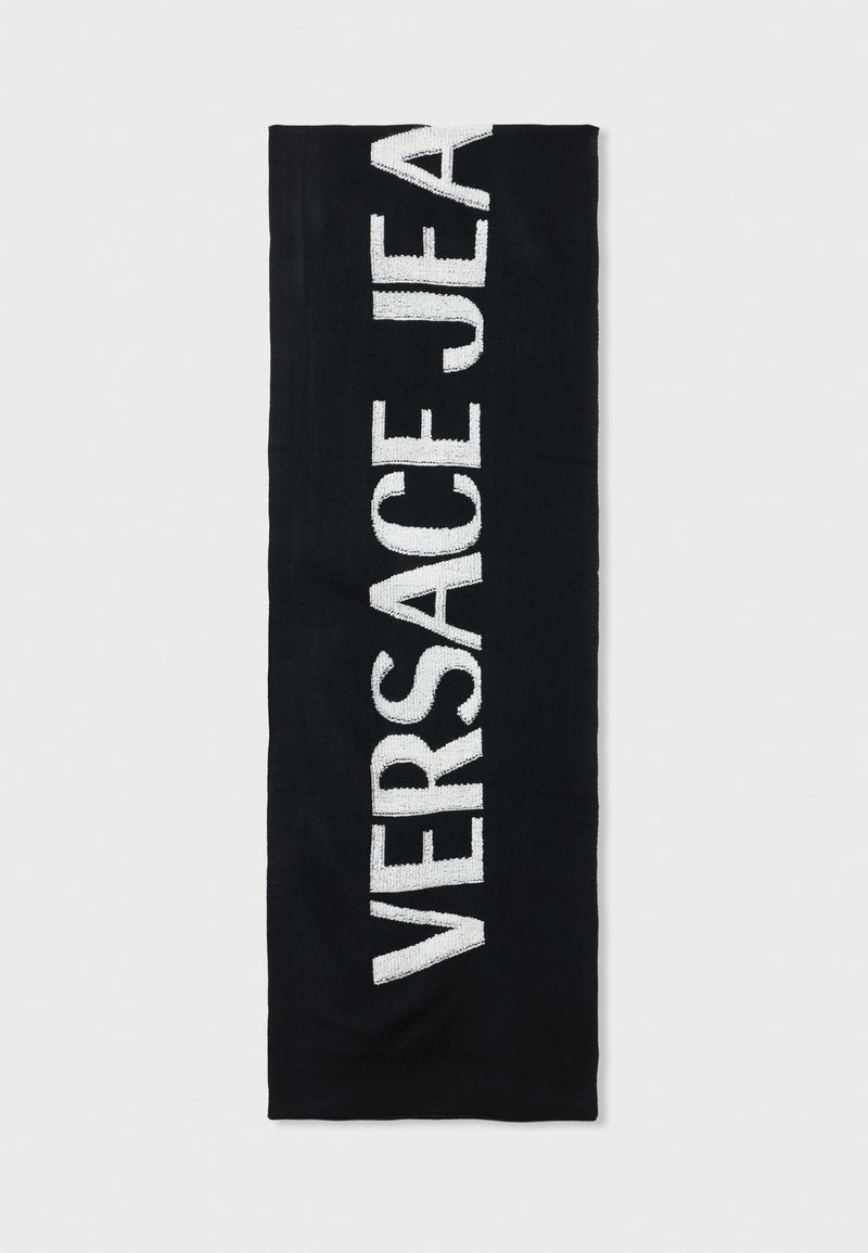 Cachecol preto feito de um tecido suave, apresentando um grande texto branco bordado que diz "VERSACE JEANS" verticalmente ao longo de um dos lados.