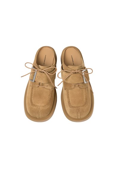 Paire de chaussures en daim beige à enfiler, avec lacets et boucles sur les côtés, bouts carrés arrondis et semelles épaisses en caoutchouc.