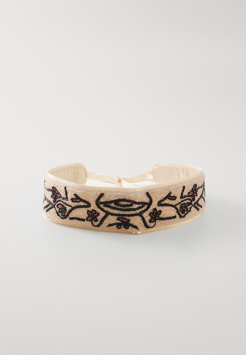 Broderte hodebånd med en beige stoffbase, utstyrt med svarte blomsterdesigns og røde aksenter, festet med en båndlås.