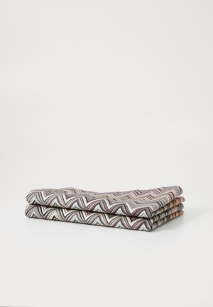 Patterned fabric with zigzag design in muted colors, stacked neatly. Material appears soft, showcasing fine textures and multiple hues.