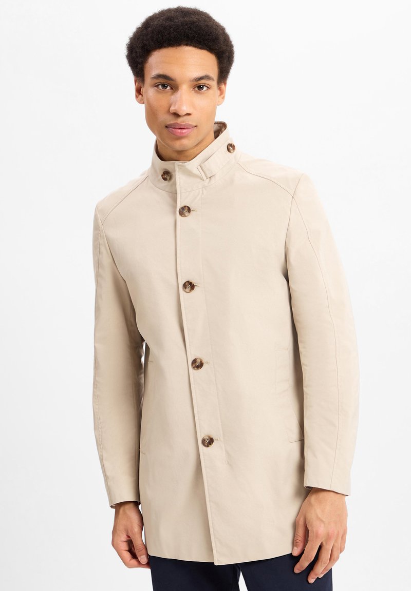 Beige trenchcoat met een hoge kraag, grote knopen, zijzakken en een gladde textuur, op maat gemaakt voor een getailleerde uitstraling.