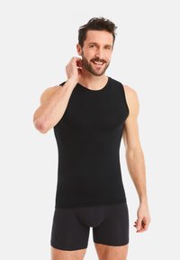 Black sleeveless undershirt made of smooth fabric, fitted design, round neckline, paired with black boxer shorts, showing a close-fitting silhouette.