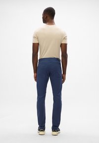 Granatowe spodnie o slim fit, wykonane z miękkiego, teksturowanego materiału. Posiadają dwie tylne kieszenie oraz paski na pasek z skórzanym akcentem.