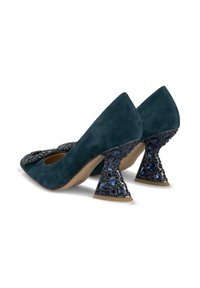 Semišové lodičky v tmavě modré barvě s ozdobnými trojúhelníkovými podpatky zdobenými modrými krystaly. Zaoblený design špičky s hladkým a elegantním povrchem.