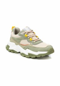 Zapatilla ligera con parte superior en verde y beige, paneles de malla y acentos amarillos. Suela blanca gruesa con exterior de olivo texturizado para mayor agarre.