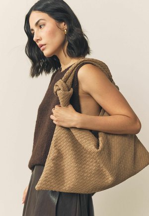 Brown woven leather bag with a knotted handle, featuring a slouchy shape and textured surface. Simple and functional design.