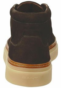 Dunkelbraune Wildleder-Stiefeletten mit hohem Kragen, hellfarbener Gummisohle und kontrastierender hellbrauner Steppnaht. GANT-Logo auf der Sohle.