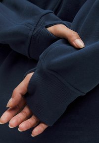 Navy blue sweatshirt featuring ribbed cuffs with thumbholes, allowing for extended coverage of hands. Soft, textured fabric visible.
