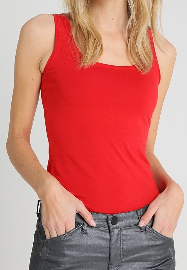 Canottiera rossa in tessuto liscio, con scollatura quadrata classica e spalline larghe. Abbinata a pantaloni grigi aderenti con tasche.
