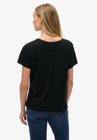 Zwart T-shirt met korte mouwen, een ronde hals, een losse pasvorm en een gladde textuur, gecombineerd met een blauwe spijkerbroek.