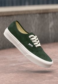 Grüne Wildleder-Sneaker im Low-Top-Design mit weißen Schnürsenkeln und Sohle. Mit einem gestickten Logotag an der Seite und einer strukturierten Oberfläche.