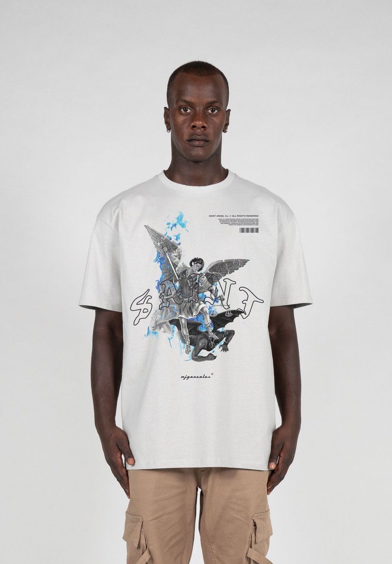 Lys grå t-shirt med et grafisk design med en engel og en dæmon, fremhævet med blå flammer og teksten "SAINT." Korte ærmer, afslappet pasform.