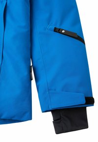 Tessuto impermeabile di giacca blu, con tasca con zip, chiusura in velcro ai polsini e fodera interna nera a contrasto.