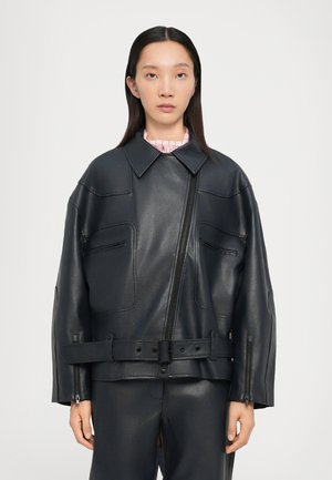 Veste en cuir noire avec un grand col, fermeture éclair à l'avant et grandes poches. Caractéristiques d'une taille ceinturée et de poignets zippés. Texture lisse.