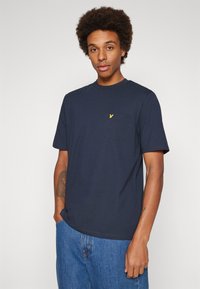 T-shirt girocollo blu navy in cotone, con tasca e logo ricamato giallo. Maniche corte e vestibilità comoda.