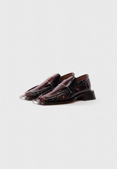 Pair of dark burgundy glossy leather loafers with low block heel and squared toe, displayed on white background.