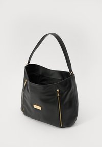 Sac à main en cuir noir avec une texture lisse, présentant deux accents de fermeture éclair dorés et une plaque de logo embossée à l'avant.