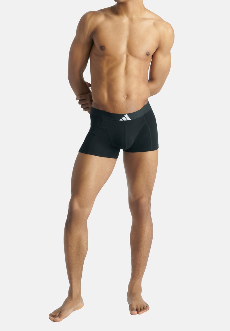 Svarta sportshorts med en figurnära design, elastisk midja med en vit logga och ett slätt tyg för komfort och flexibilitet.