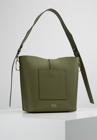 Olivově zelená kabela typu bucket s přední kapsou, nastavitelným ramenním popruhem, zlatým kováním a logem "ZAC ZAC POSEN" na bílém pozadí.