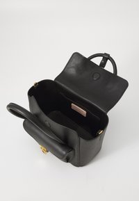 Black leather handbag with a textured surface, open top, and interior pockets. Features gold hardware and a small logo tag in pink.