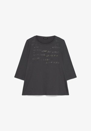 Tummanharmaa pitkähihaista paita, jossa pyöreä pääntie ja pieniä, hajanaisia hopeanvärisiä tekstejä sekä koristeita etuosan yläosassa.