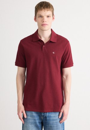 Maroon polo shirt made of soft fabric, featuring a classic collar, short sleeves, and a small embroidered logo on the left chest.
