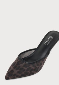Mule noire à bout pointu avec imprimé léopard marron et design slip-on, étiquetée vegan et fabriquée en Belgique.