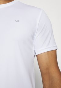 Witte T-shirt met korte mouwen, gemaakt van zachte stof, met een subtiele CK-logo geborduurd op de borst. Eenvoudig ontwerp met een ronde halslijn.