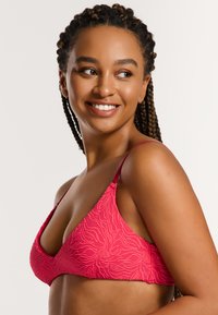 Rosa Bikini-Oberteil mit einem strukturierten Blumenmuster, dünnen Trägern und einer dreieckigen Form, entworfen für eine taillierte Passform.