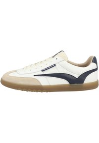 Zapatillas de cuero blancas y marinas con una puntera de ante beige, lengüeta de malla texturizada, cordones planos y suela de goma con patrón de zigzag.