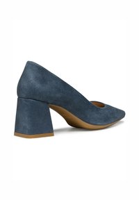 Pump blu in suede con punta affusolata e tacco spesso. Il materiale sembra morbido con una finitura strutturata. Le suole sono color nocciola.