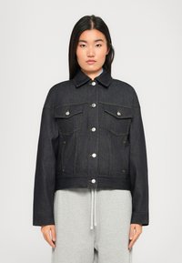 Mørk denimjakke med krave, frontlukning med knapper, to klaplommer og kontraststænkdetaljer. Kort design med store ærmer.