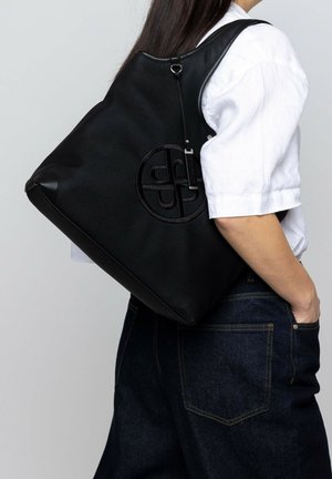 Sac fourre-tout noir en matériau texturé, avec un logo embossé circulaire, une bandoulière et un design structuré.