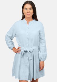 Abito camicia azzurro chiaro in tessuto textured, con cintura legata in vita e maniche lunghe con polsini abbottonati.