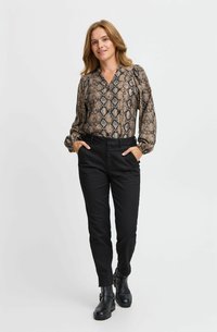 Juodi prigludę kelnės su smėlio ir juodos spalvos gyvatės rašto bluzone, turinčia V formos iškirpę ir susiraukšlėjusiomis rankovėmis. Juodos aulinės batai iki kulkšnies.