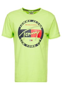 Neon zielona bawełniana koszulka z okrągłym nadrukiem graficznym, na którym znajduje się napis "Tommy Jeans" oraz "Nowy Jork", ozdobiona czerwonymi i czarnymi detalami.