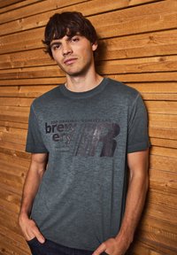 Grå bomullströja med ett grafiskt tryck som har texten "brewery" och "220 ORIGINAL QUALITY LAB" i mörka toner, med rund halsringning.