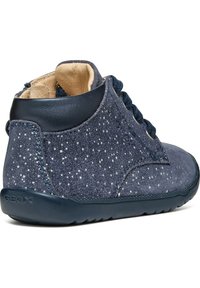 Dark blue suede ankle boot with speckled detailing, textured surface, round toe, and navy accents. Features lace-up closure and rubber sole.