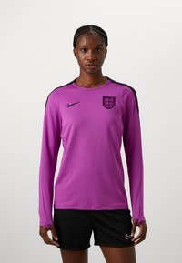 Fialová tréninková košile s dlouhým rukávem s logem Nike a erbem Anglie, s černými akcenty na ramenou a hladkou, lehkou texturou.