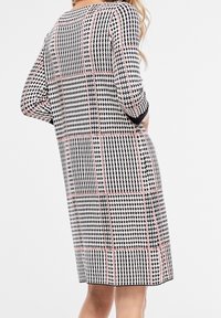 Robe à motif pied-de-poule noir et blanc avec des accents roses et rouges, manches trois-quarts et une silhouette droite. Tissu texturé.