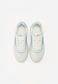 Sneaker bianche con accenti azzurri chiaro, punte perforate, lacci piatti e una suola in gomma texture. Logo visibile sui lati.