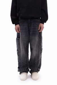 Χαλαρά σκούρα γκρι cargo παντελόνια με πολλαπλές τσέπες, διακριτική υφή και αντιθετικές ραφές, σε συνδυασμό με λευκά παπούτσια χωρίς κορδόνια.