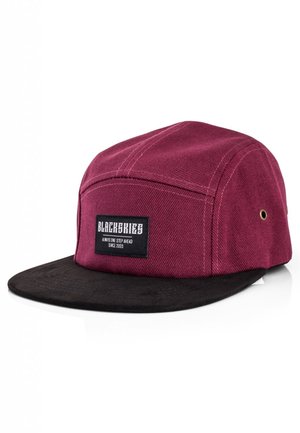 Maroon canvas cap with a black suede brim. Features a rectangular logo patch on the front, gold eyelets, and flat design.