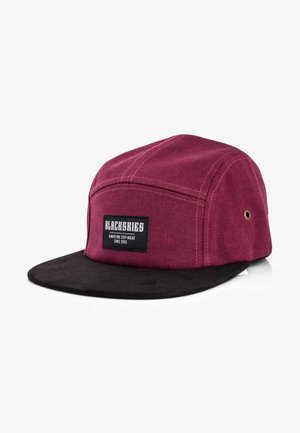 Maroon canvas cap with a black suede brim. Features a rectangular logo patch on the front, gold eyelets, and flat design.