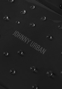 Fekete, texturált szöveten vízcseppek és a "JOHNNY URBAN" dombornyomott szöveg található, így modern és funkcionális dizájnt kölcsönözve.