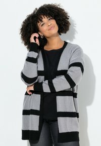 Harmaa ja musta raidallinen neulejakku, jossa on rento istuvuus, auki oleva etuosa ja pitkät hihat. Ribbaatut hihansuut ja helma tuovat tekstuuria.