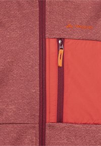 Rote und graue Jacke aus strukturiertem Stoff. Verfügt über eine mit Reißverschluss gesicherte Brusttasche mit orangen Akzenten. Markenlogo in Orange dargestellt.